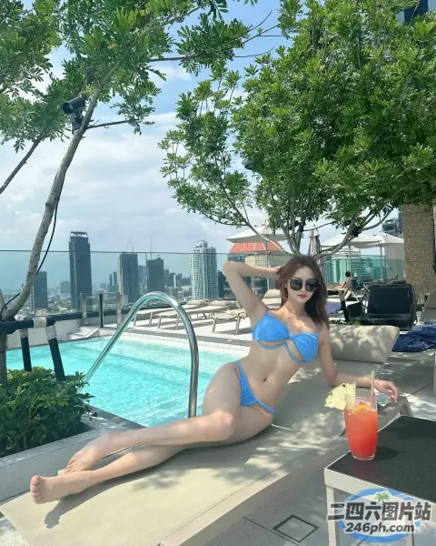 穿着蓝色比基尼的女人坐在游泳池旁边的窗台上