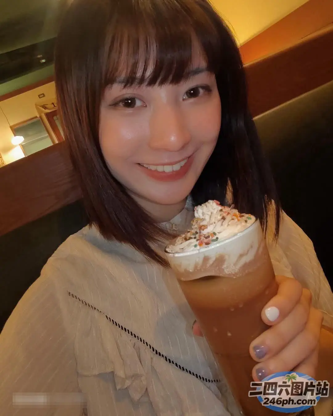 面带微笑的女人拿着一杯咖啡，里面有生奶油和糖屑