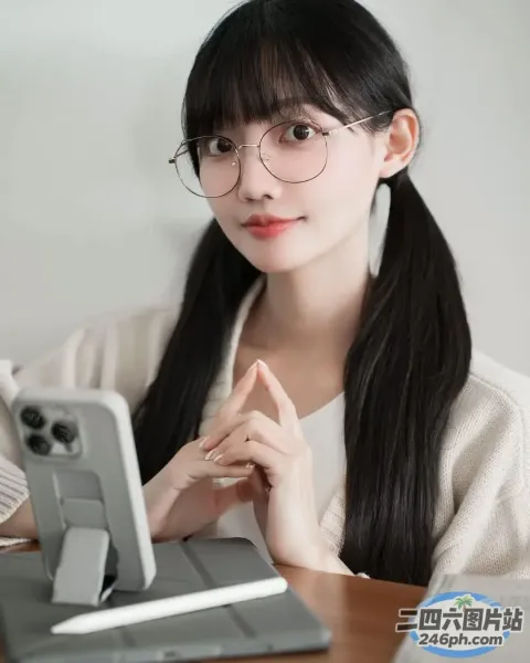 戴眼镜的阿拉夫德女人坐在桌子旁，手里拿着笔记本电脑