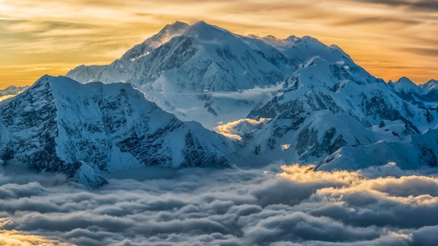 白雪皑皑的群山和云彩，背景是日落