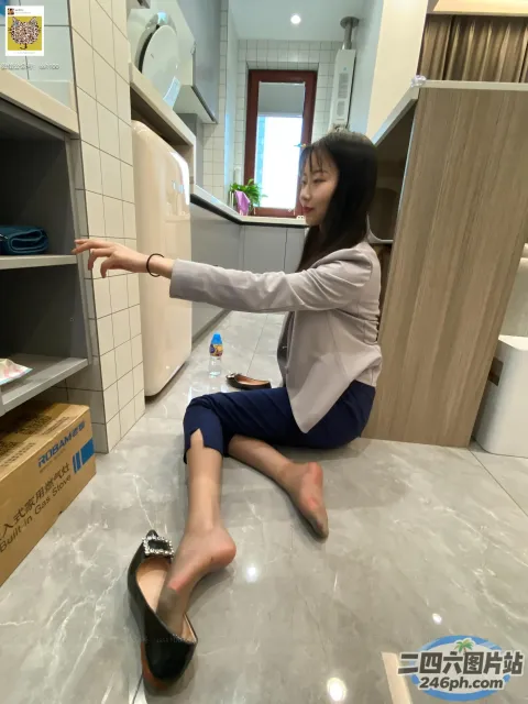 坐在厨房地板上的女人伸手去拿东西