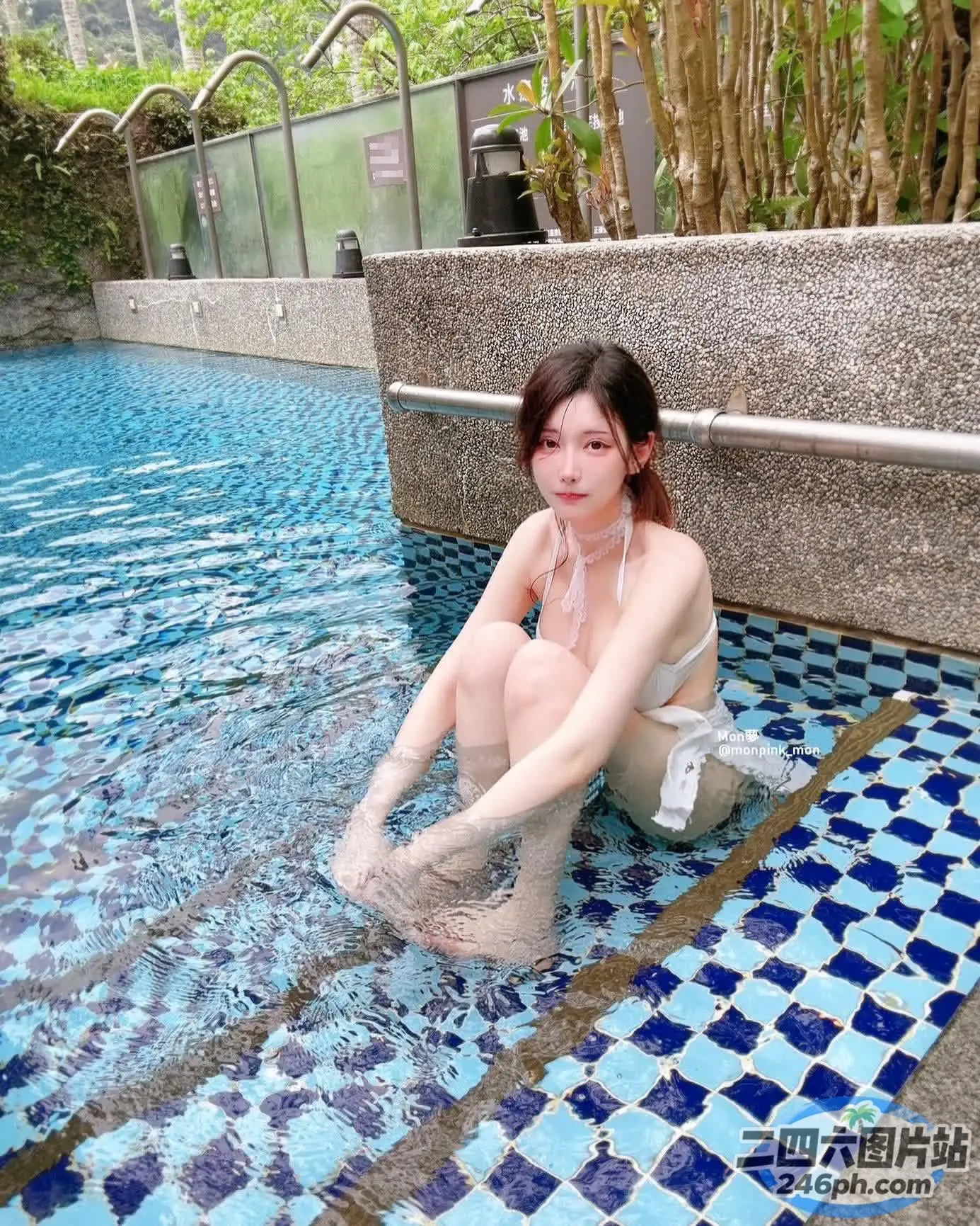 有一个女人坐在游泳池里，双腿交叉