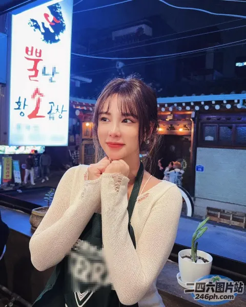 有个女人坐在桌子旁，手里拿着杯子