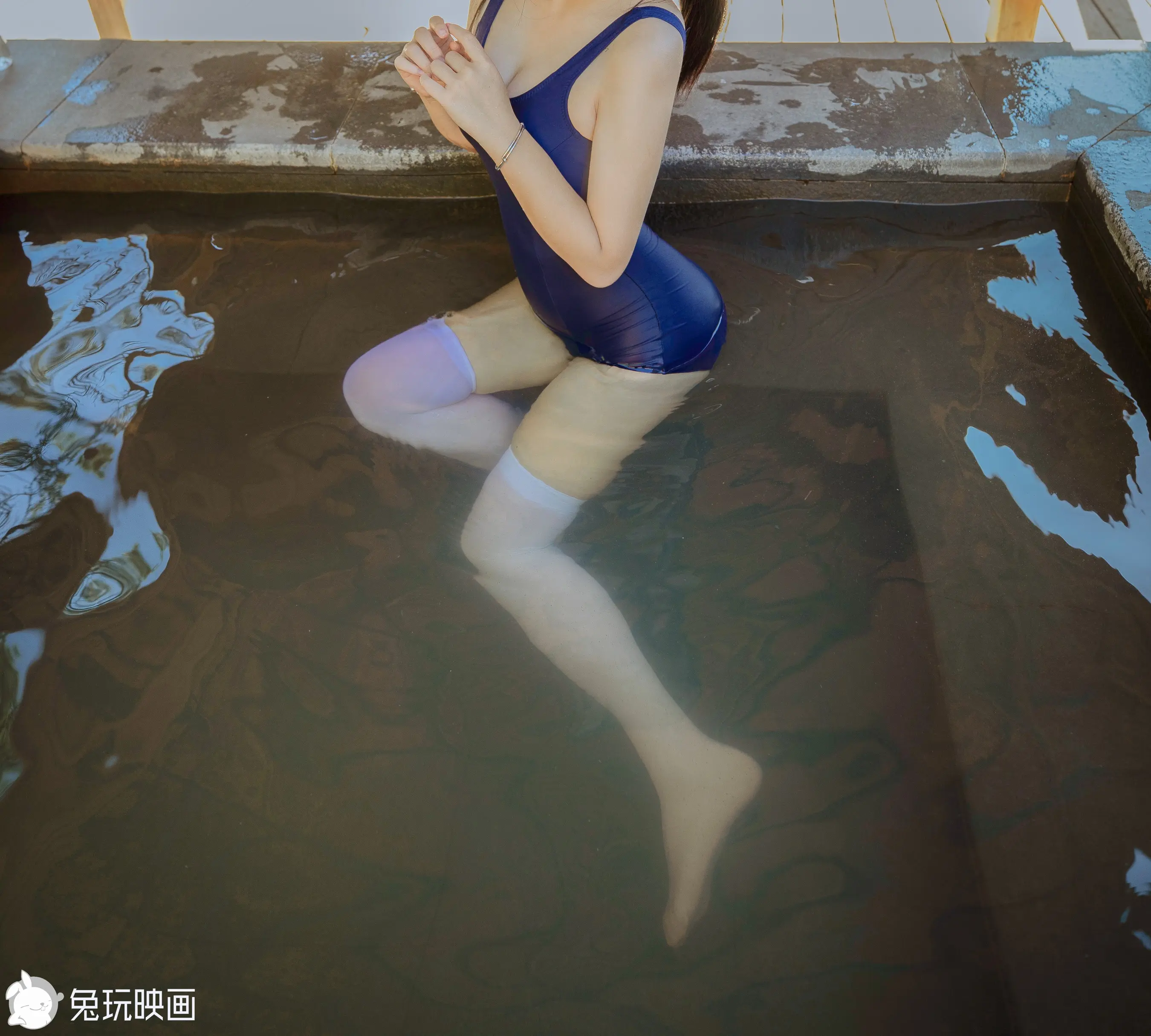 泳池里坐着一个穿着蓝色泳衣的女人