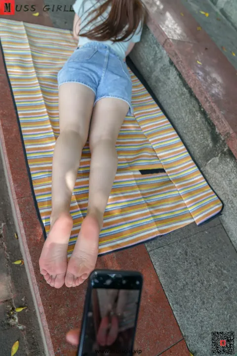 阿拉菲德女人躺在地上的毛巾上，双脚抬起
