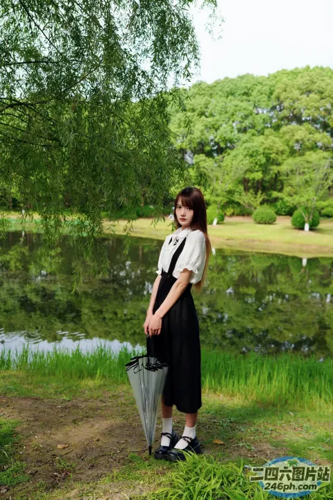 池塘边站着一个女人，手里撑着伞