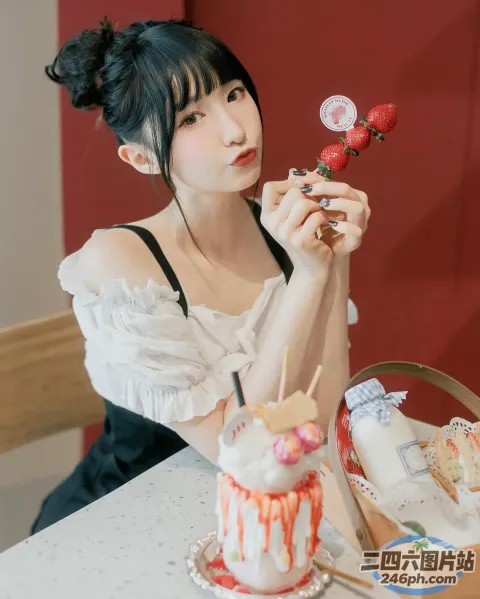 桌上坐着一个女人，手里拿着一个蛋糕和一朵花