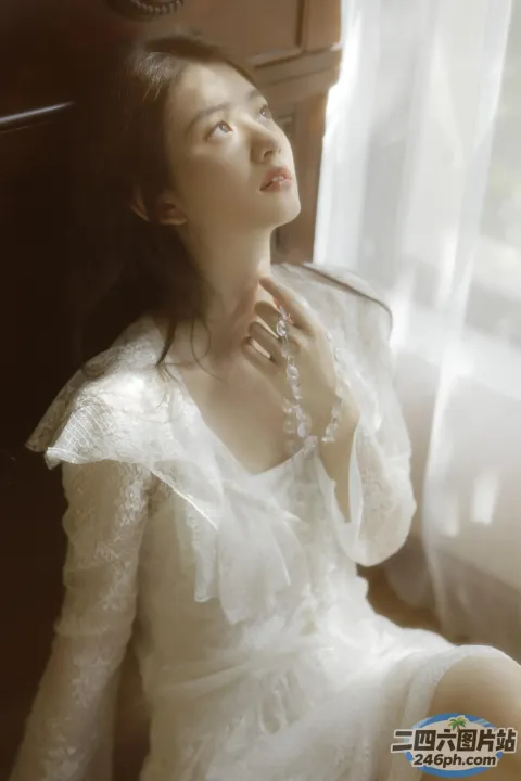 有一位身穿白色连衣裙的女士坐在椅子上