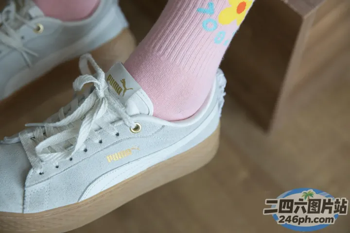 有人穿着一双白色运动鞋和粉红色袜子