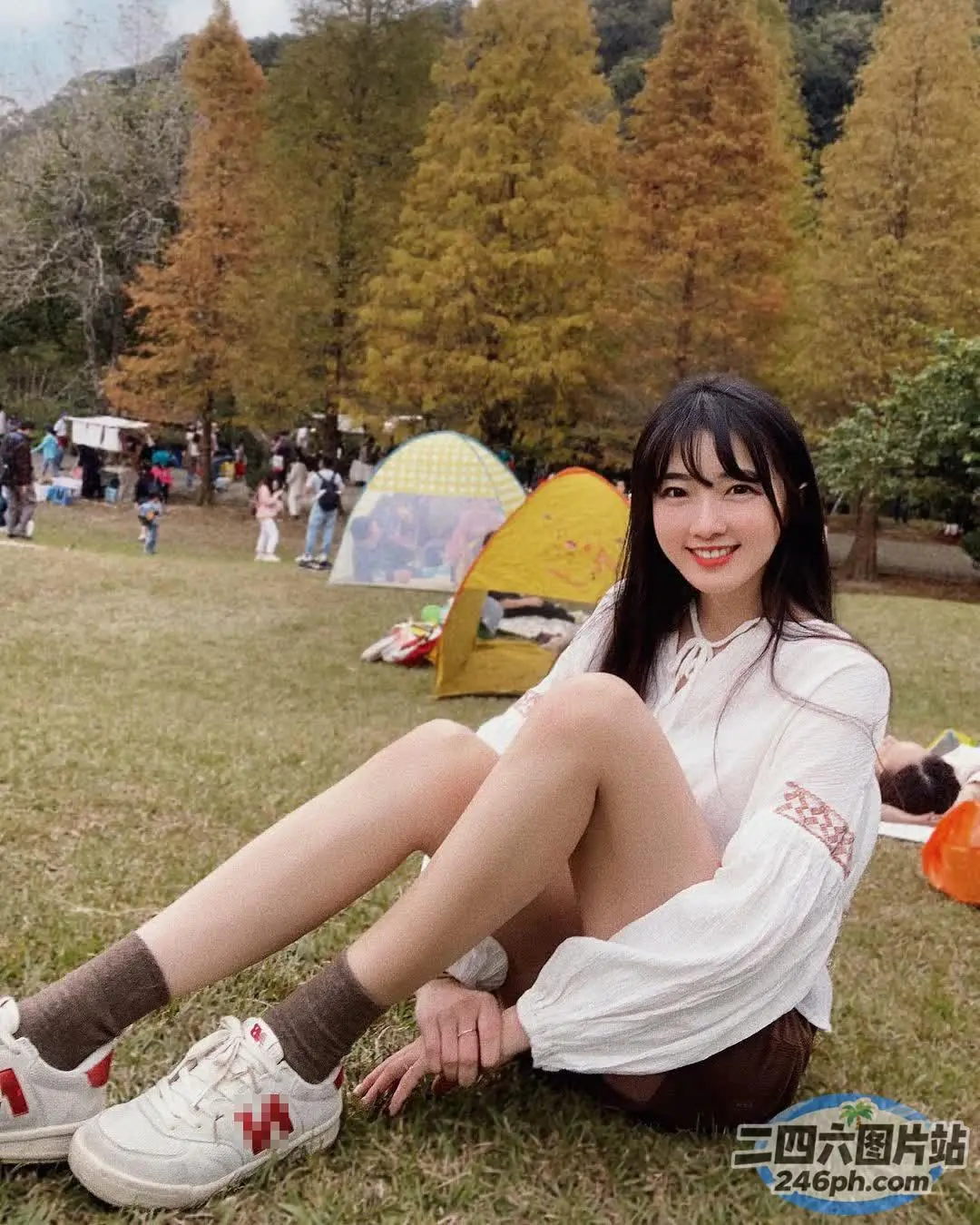 有一个女人坐在草地上，双腿交叉