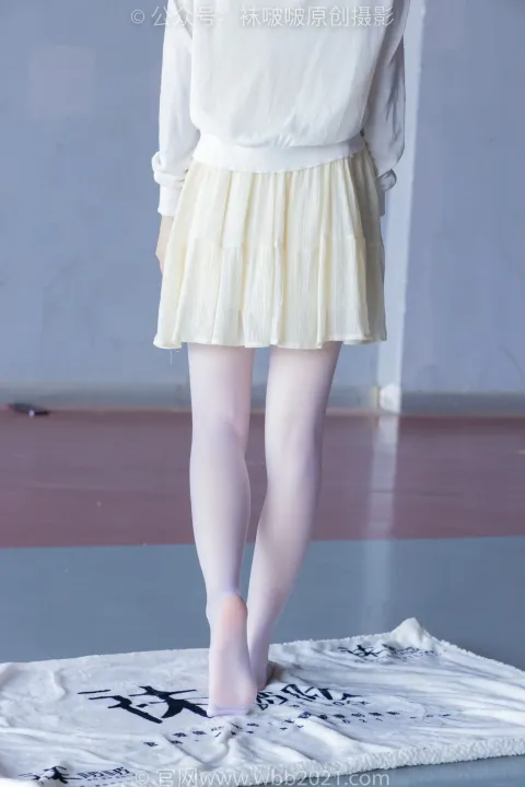 一个穿着白衬衫和裙子的女人站在白色地毯上