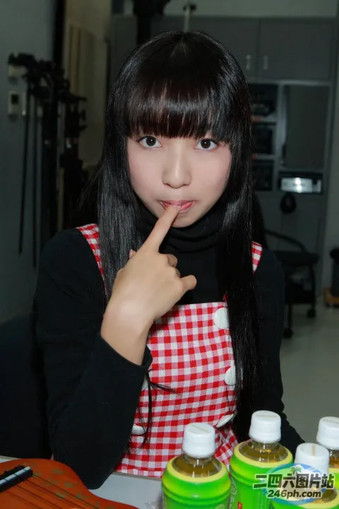 有一位年轻女子坐在一张桌子旁，手里拿着一瓶液体