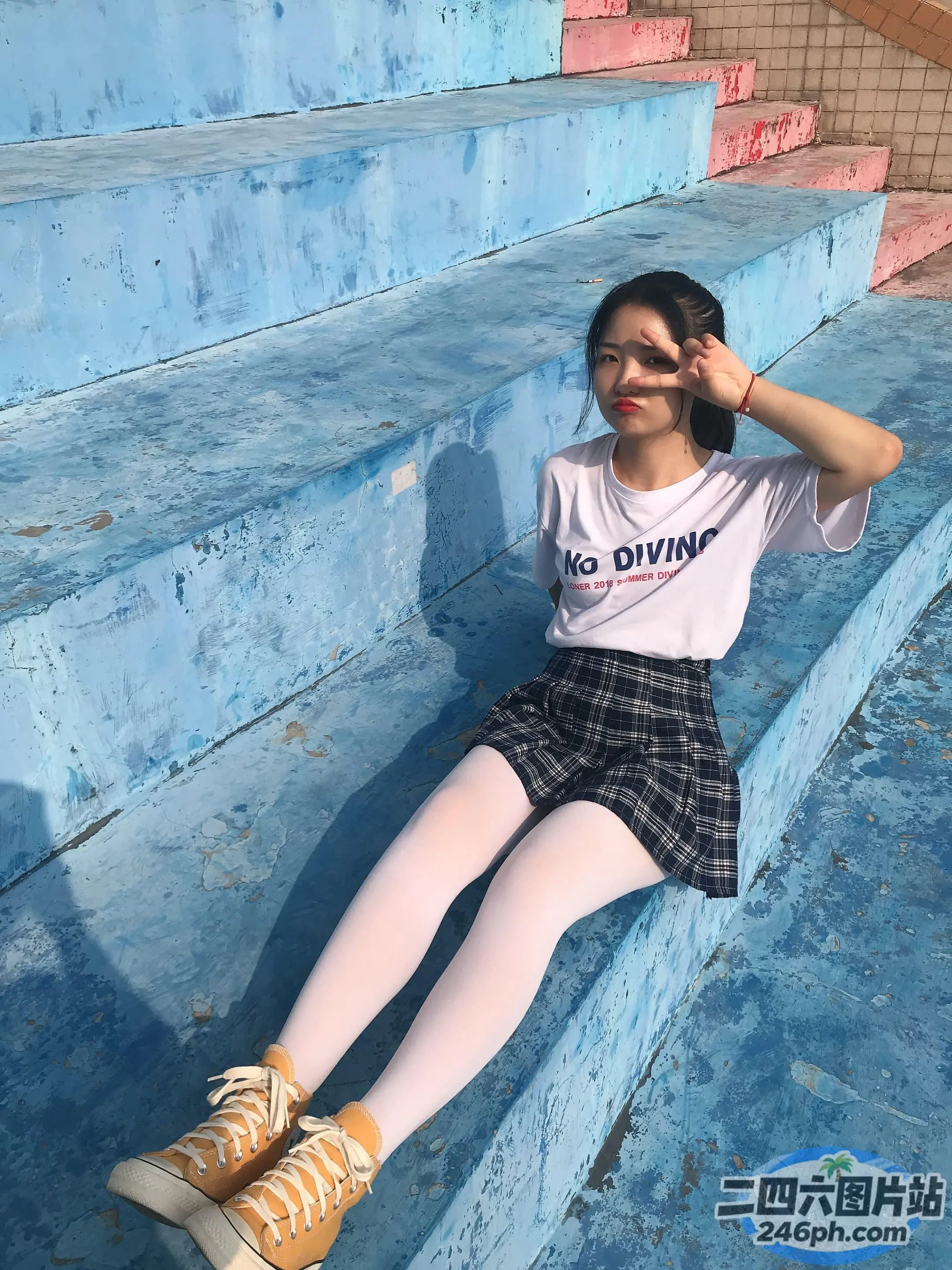 有一个女人坐在蓝色的台阶上，双腿交叉
