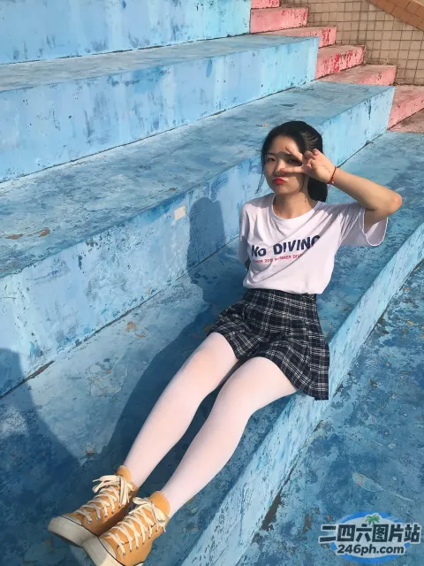 有一个女人坐在蓝色的台阶上，双腿交叉