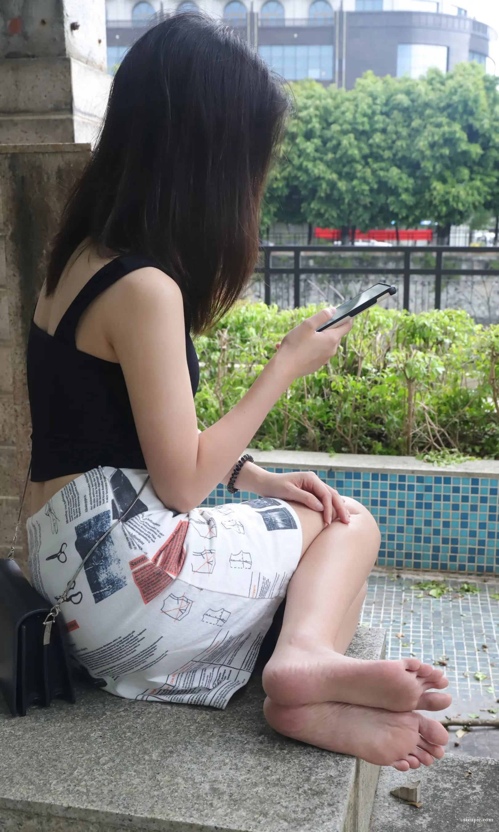 阿拉菲女人坐在窗台上用手机