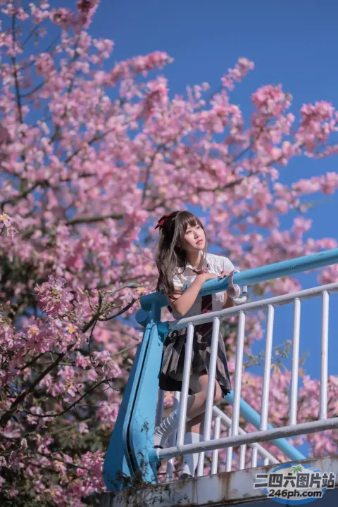 有一个女人站在桥上，背景是一棵樱花树