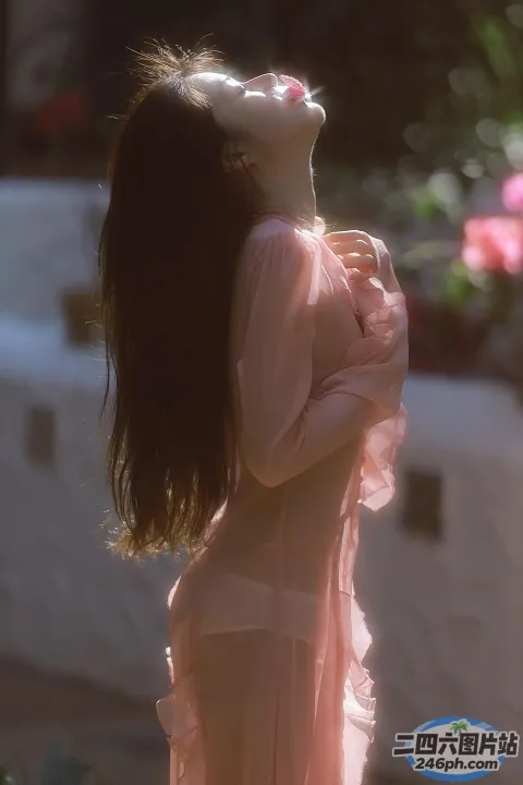 一个穿着粉红色连衣裙的女人站在一栋建筑前的特写
