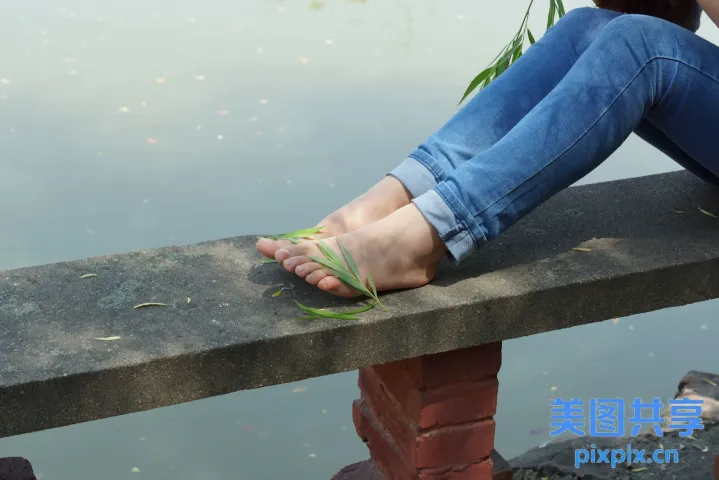 有人坐在长凳上，双脚踩在水边
