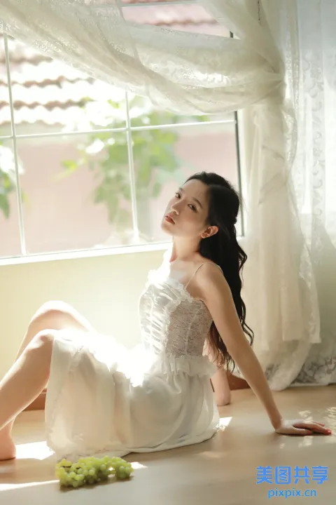 地板上坐着一个穿着白色连衣裙的女人