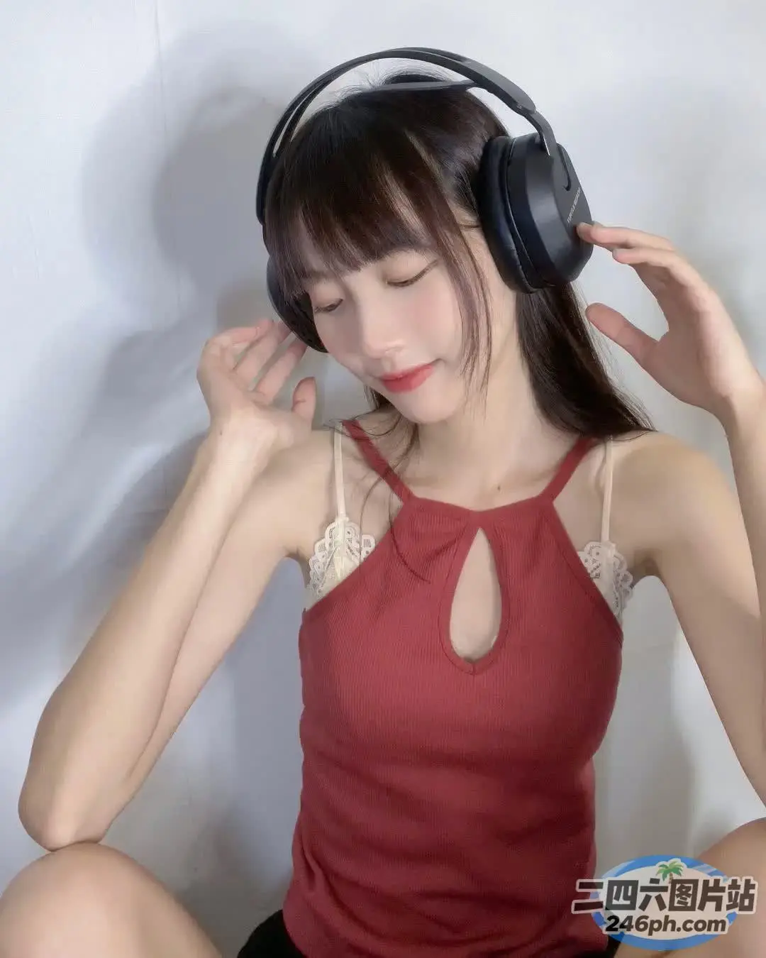 戴着耳机、穿着红色上衣坐在床上的阿拉夫德女人