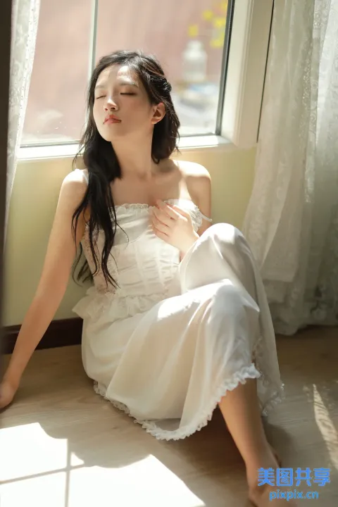 地板上坐着一个穿着白色连衣裙的女人