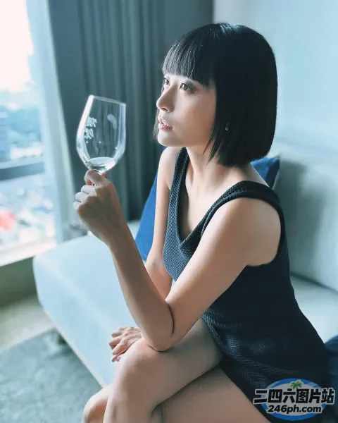 阿拉菲女人坐在沙发上，手里拿着一杯酒