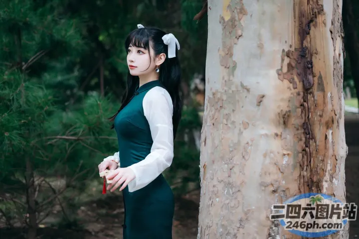 树旁站着一个穿着绿色连衣裙的女人