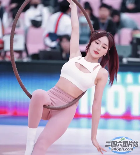 一个穿着白色上衣和粉红色裤子的女人正在用铁环做一个把戏