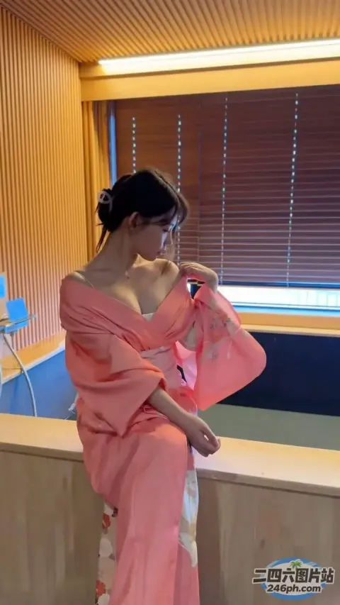 穿着粉红色和服的女人坐在浴室的窗台上