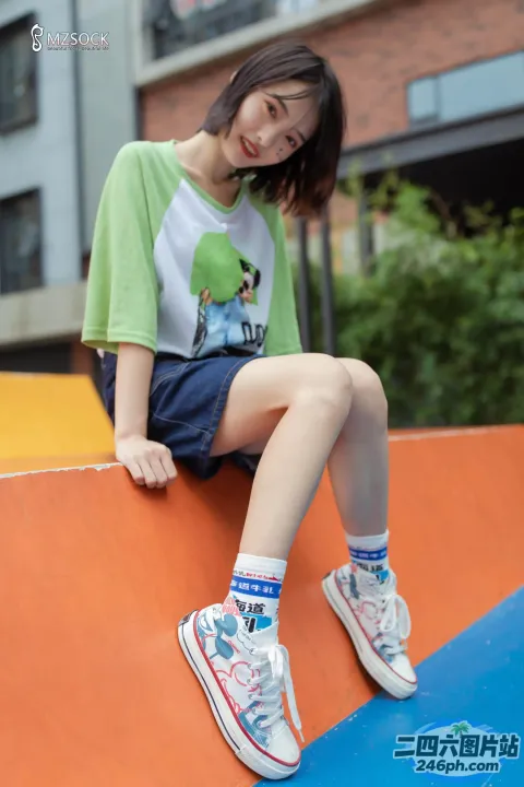 阿拉菲穿着绿色衬衫和蓝色短裤坐在墙上