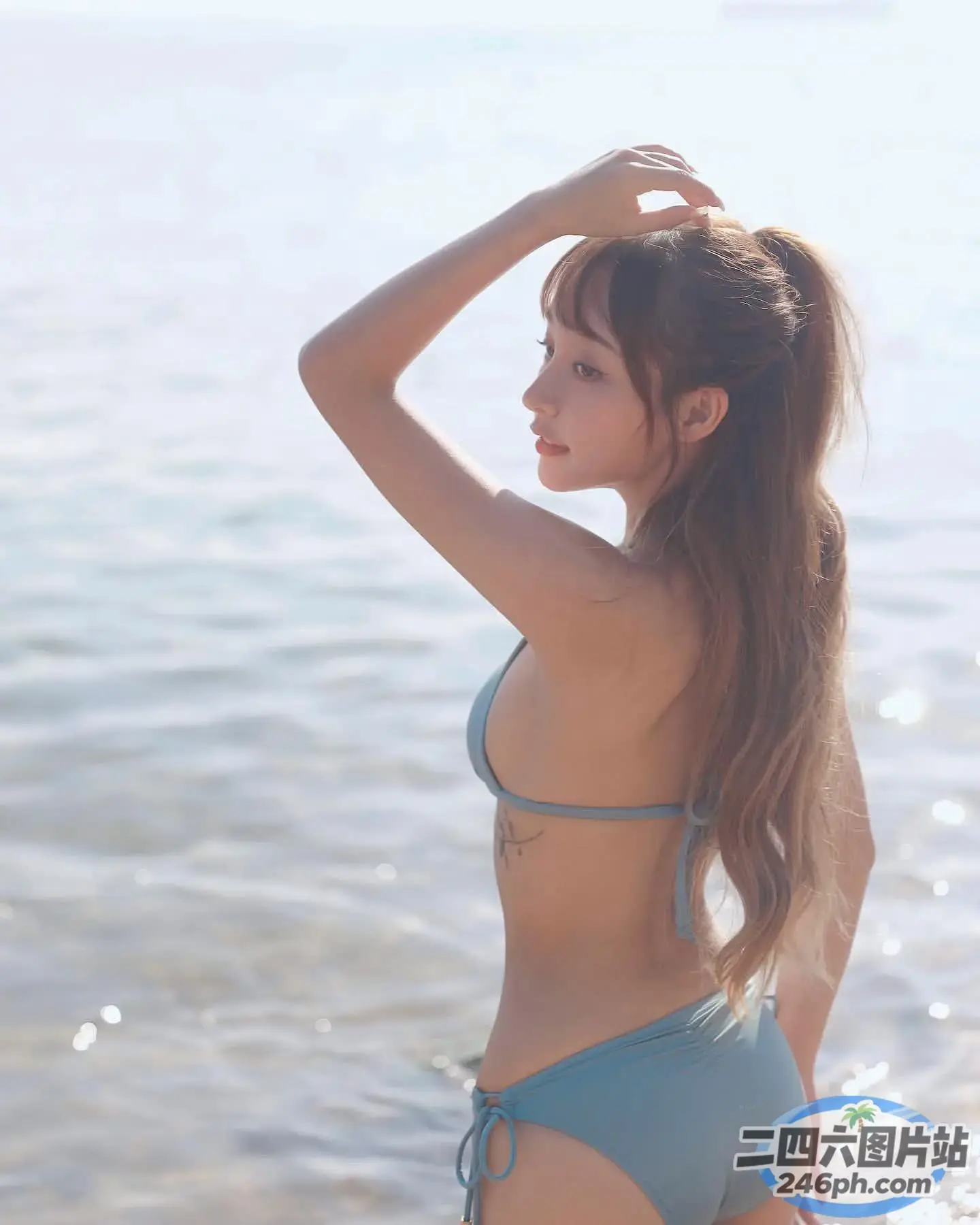 一个穿着蓝色比基尼的女人站在海边的海滩上