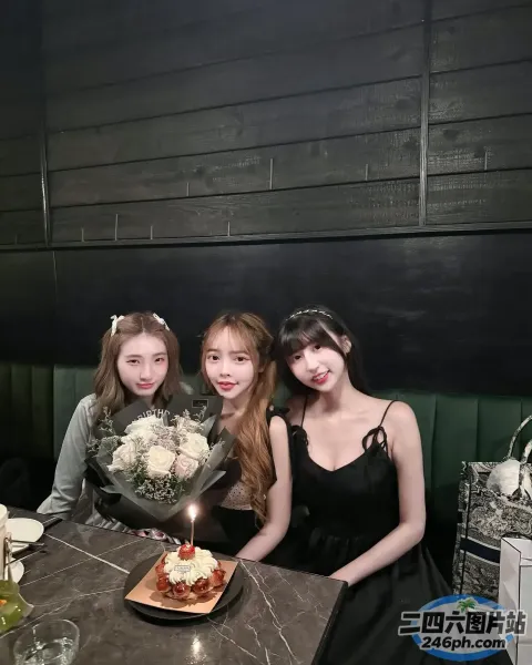 三个女孩坐在一张桌子旁，手里拿着蛋糕和鲜花