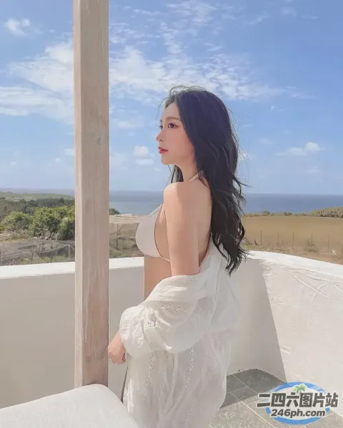 一个穿着白色连衣裙的女人坐在阳台上，可以看到风景