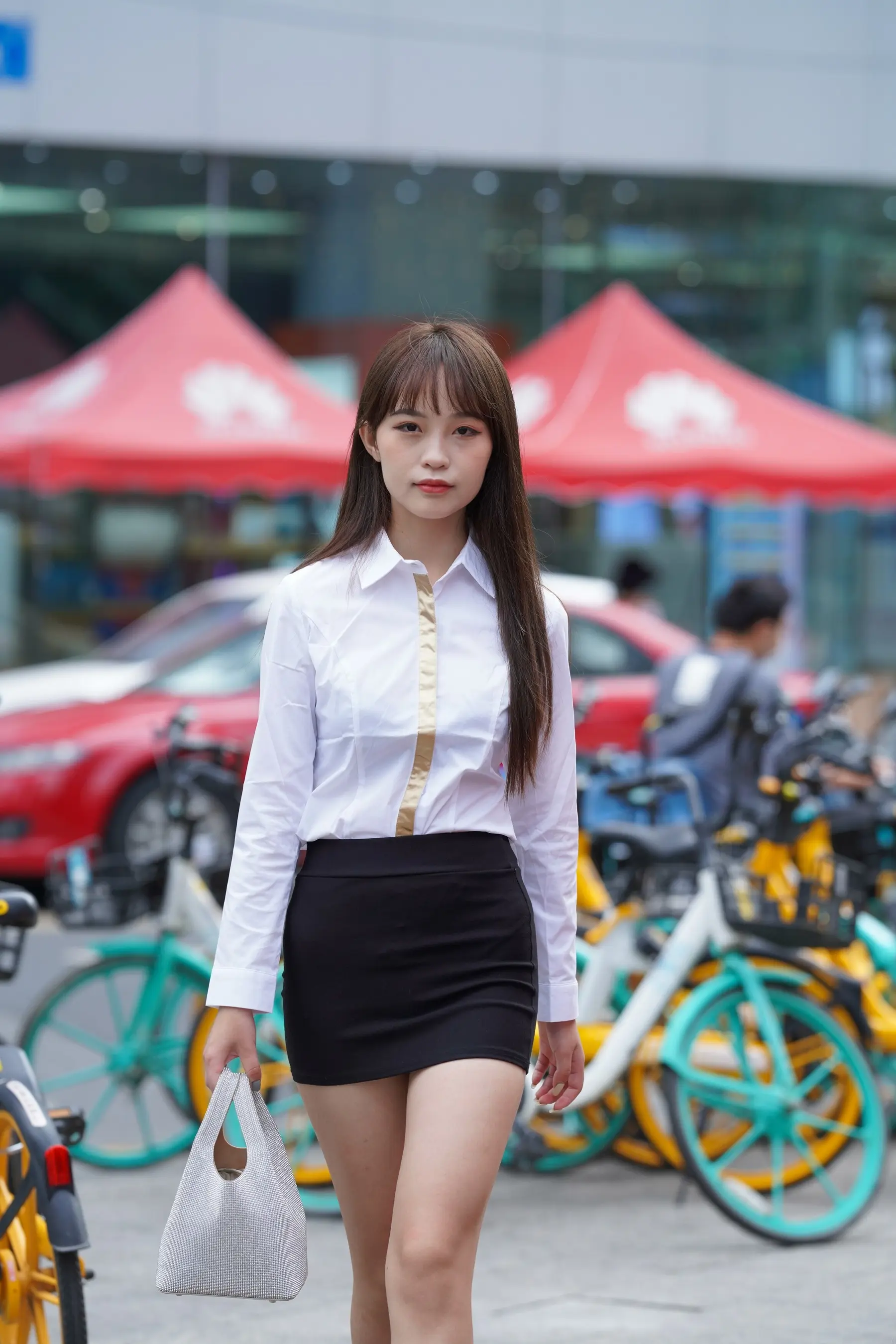 穿着裙子和白衬衫走在街上的女人