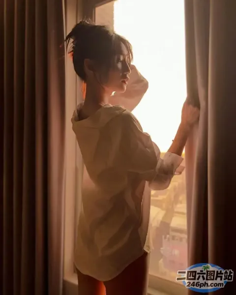 有一个女人站在窗边望着外面的太阳