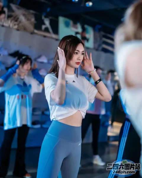 一个穿着白衬衫和蓝色紧身裤的女人站在镜子前