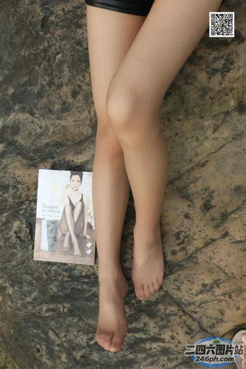坐在岩石上的阿拉菲德女人，手里拿着一本书和一双凉鞋