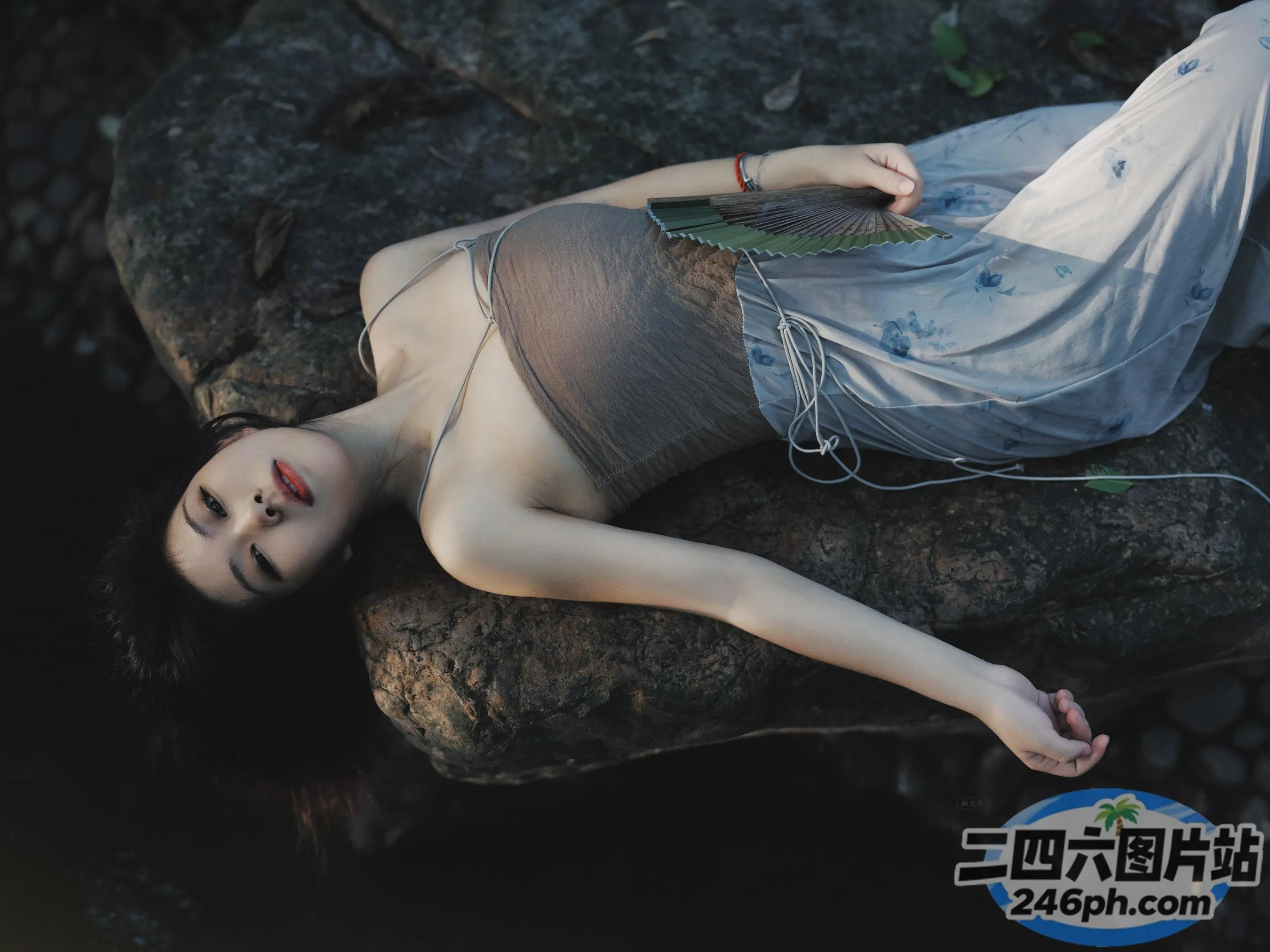 戴着耳机躺在岩石上的 arafed 女人
