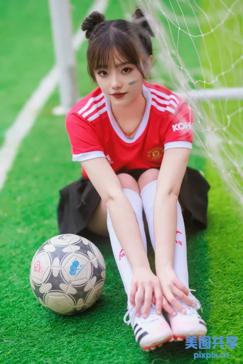 拿着足球坐在地上的阿拉菲女孩