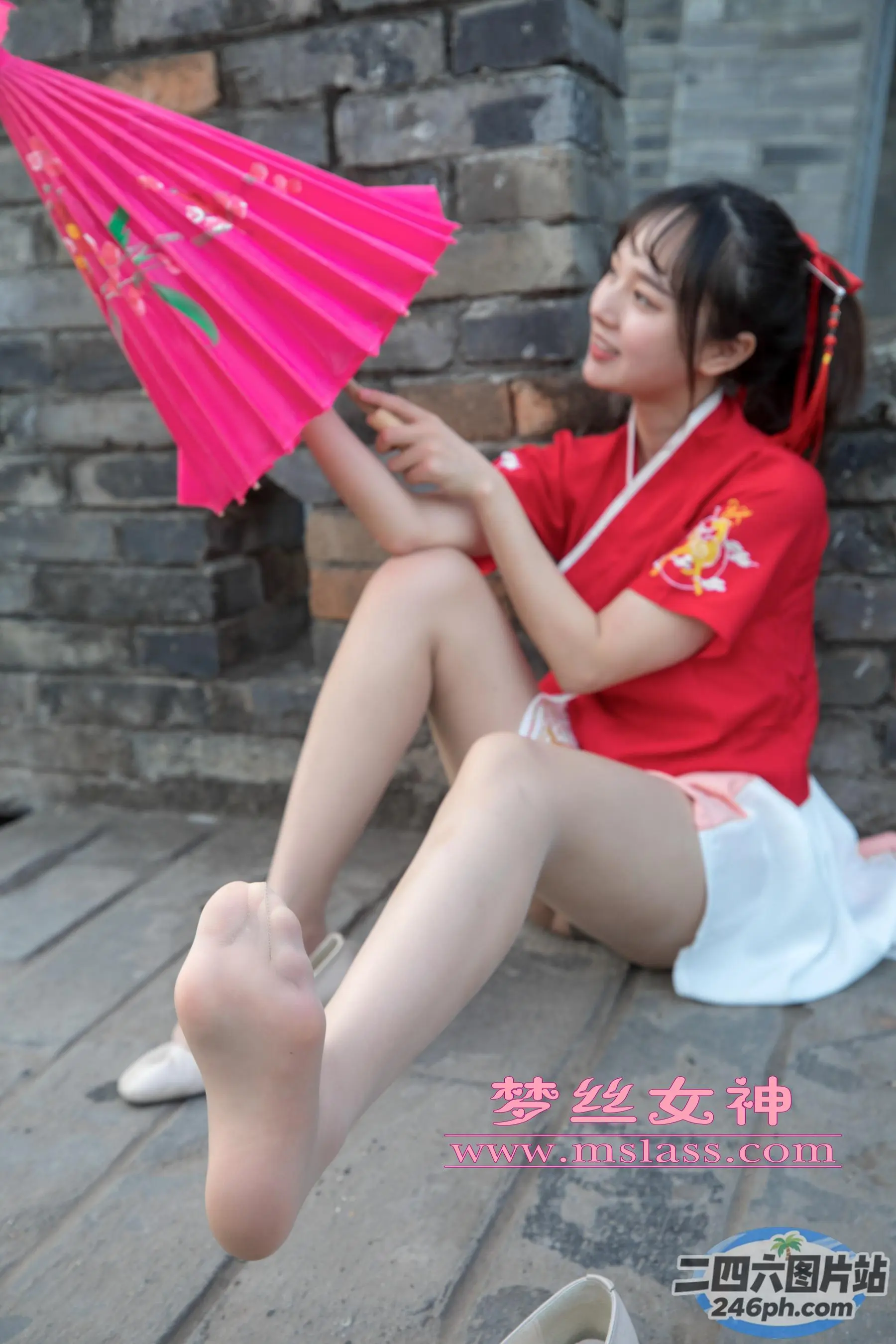 阿拉菲坐在地上，手里拿着一把粉红色的雨伞和一双鞋