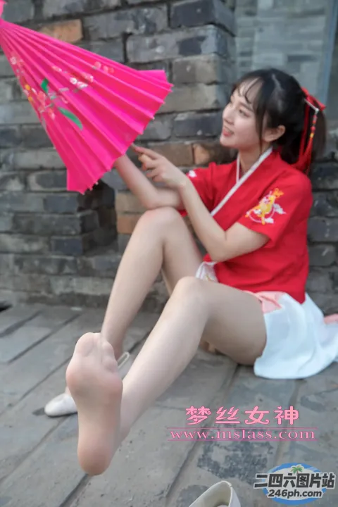 阿拉菲坐在地上，手里拿着一把粉红色的雨伞和一双鞋
