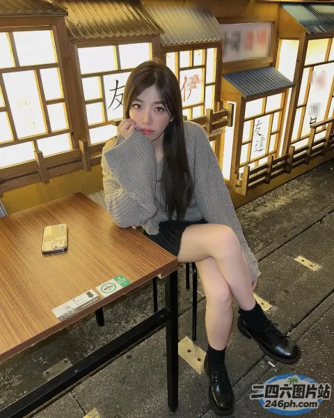 阿拉菲女子坐在桌子旁，手里拿着手机
