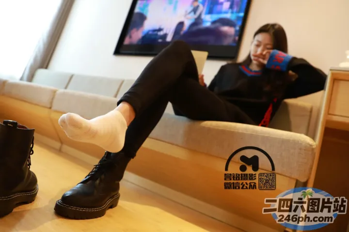 坐在沙发上的女人，双脚抬起，脚踩一双黑色靴子