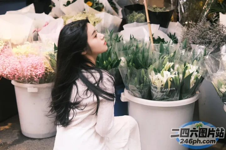 地上坐着一个女人，旁边是一束花