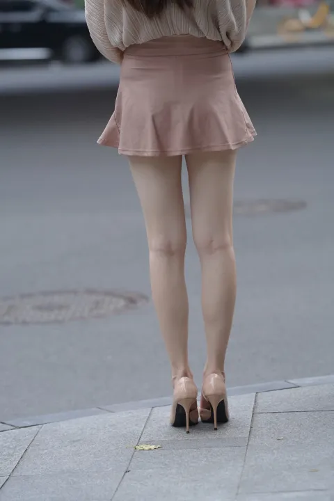 穿着裙子和高跟鞋的 Araffed 女人走在街上