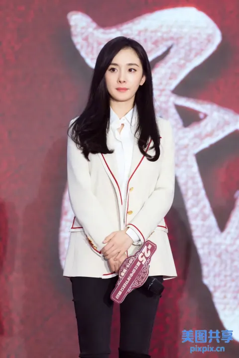 身穿白色夹克和黑色裤子的阿拉夫女人拿着粉红色的钱包