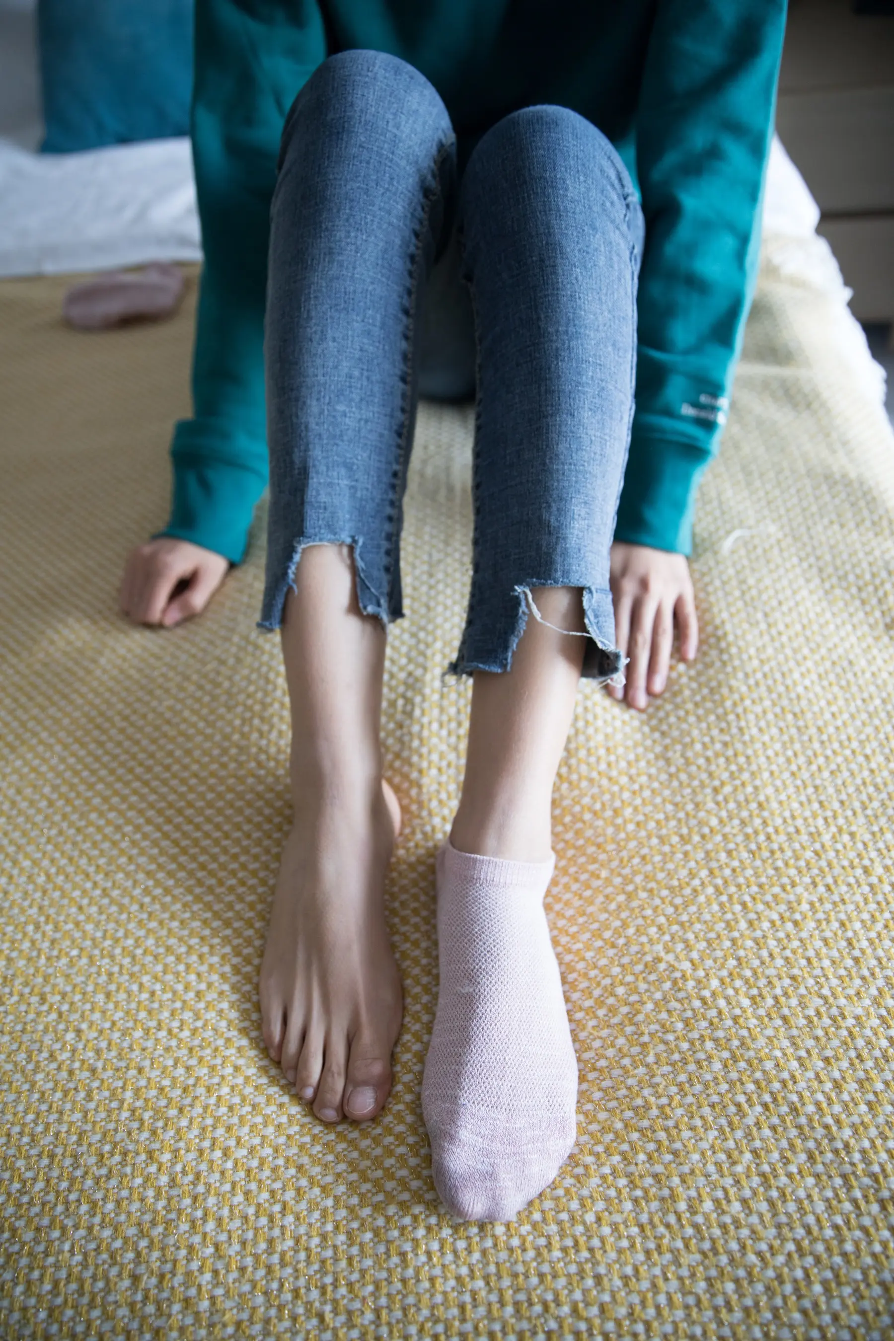 一个女人坐在床上，手里拿着一双袜子