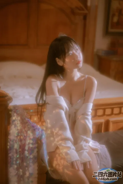 有一个女人坐在床上，上面盖着一条毯子