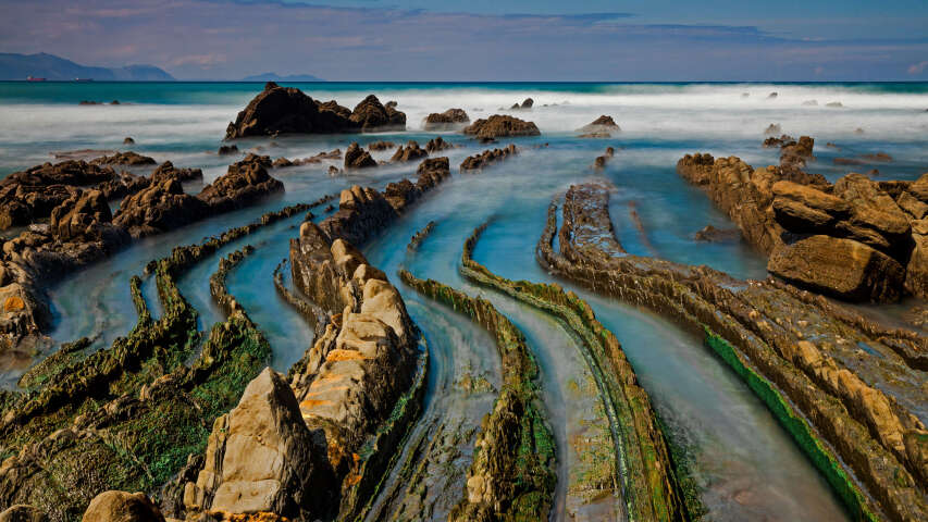 岩石海岸线，绿藻覆盖的岩石和海浪