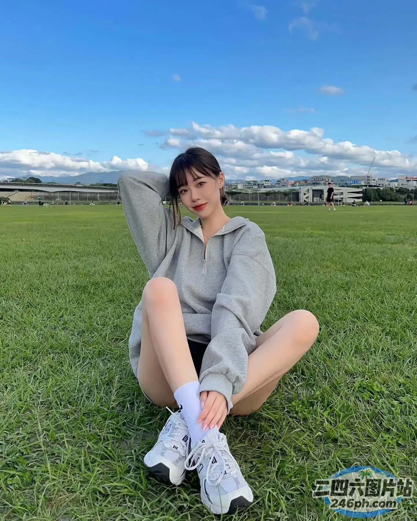 一个女人坐在田野的草地上，双脚抬起